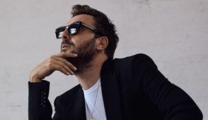 Cesare Cremonini con espressione seria e occhiali da sole