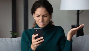 Donna con smartphone in mano ed espressione infastidita