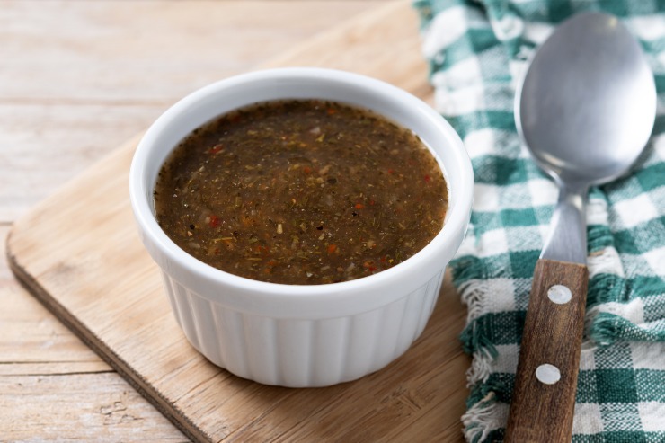 Salsa chimichurri verde su un tagliere di legno accanto a un cucchiaio e un tovagliolo