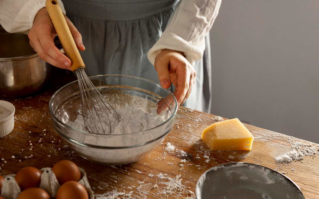 Una persona prepara un dolce co diversi ingredienti sul tavolo