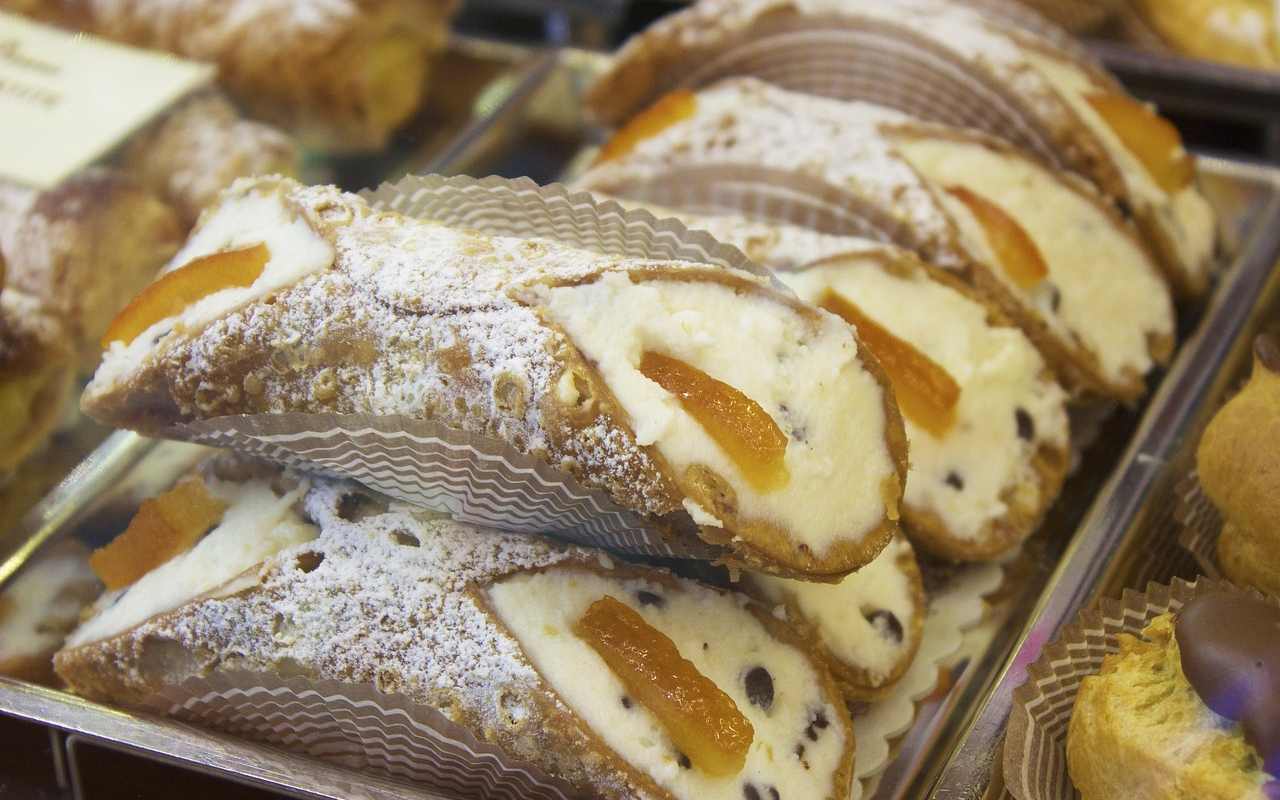 Un vassoio di cannoli siciliani dietro la vetrina di una pasticceria